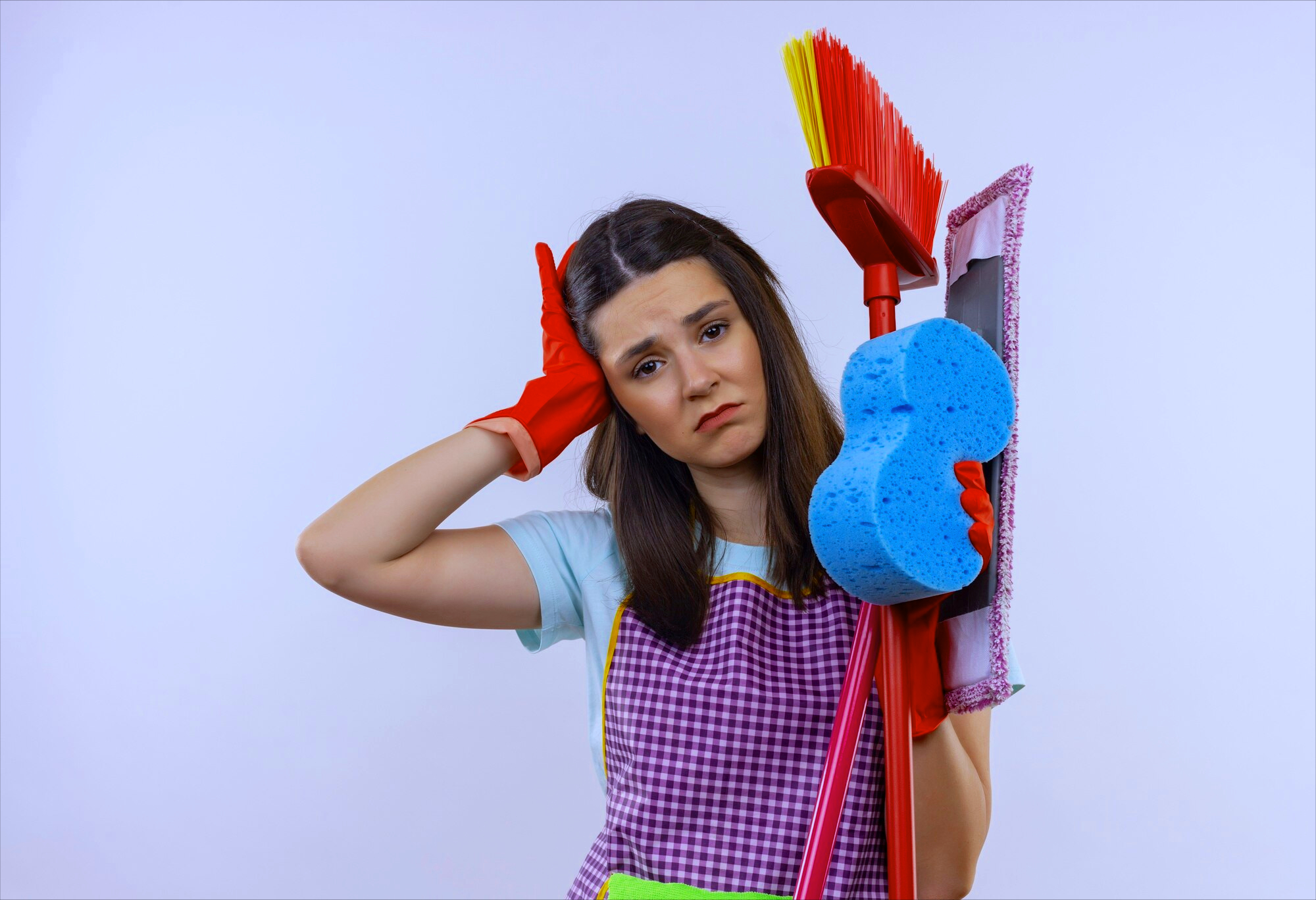 House cleaning service mistakes. Frustrated house cleaner in gloves and uniform, holding her head in confusion.