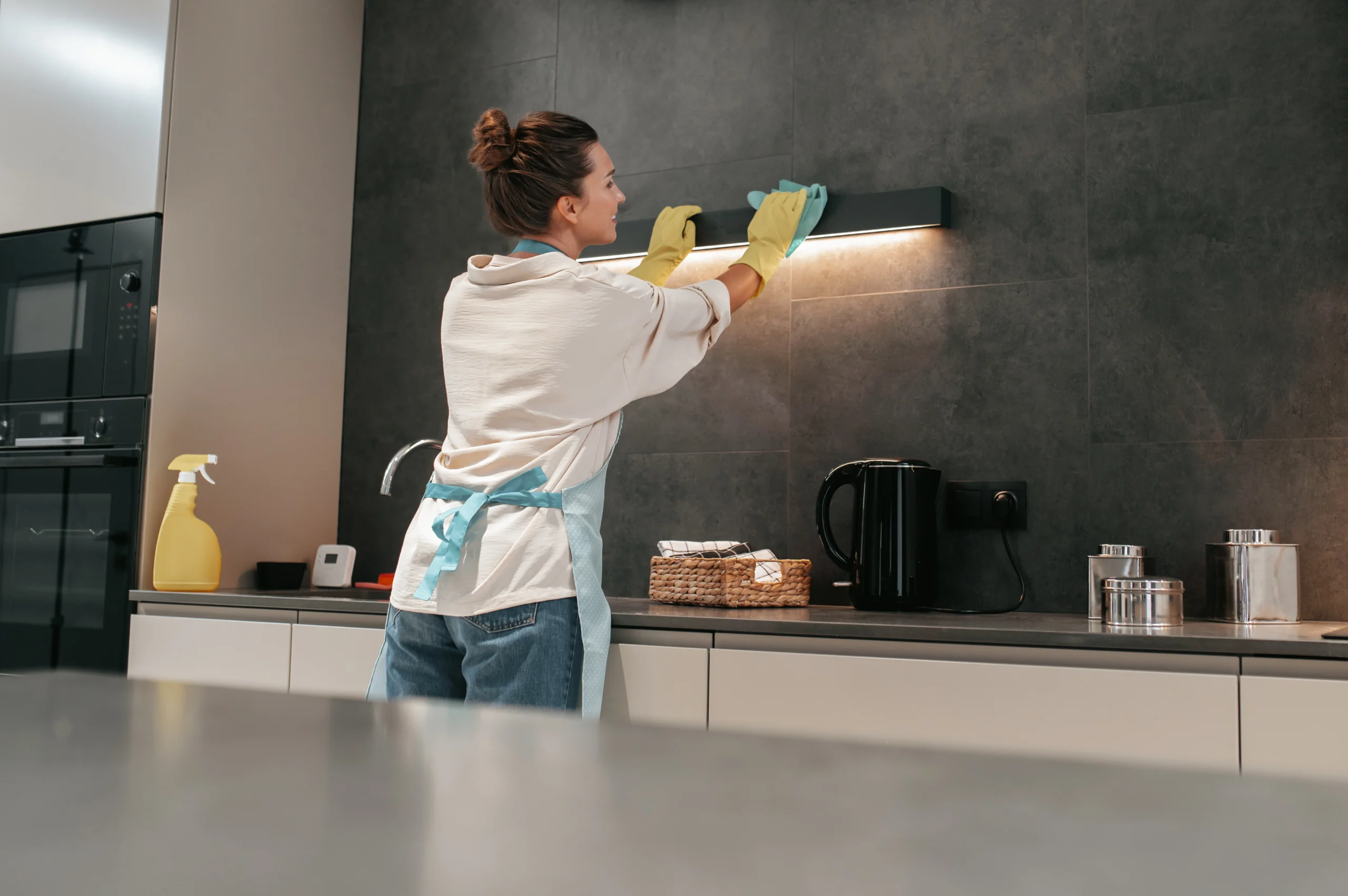 Professional cleaner performing deep cleaning tasks in a modern kitchen