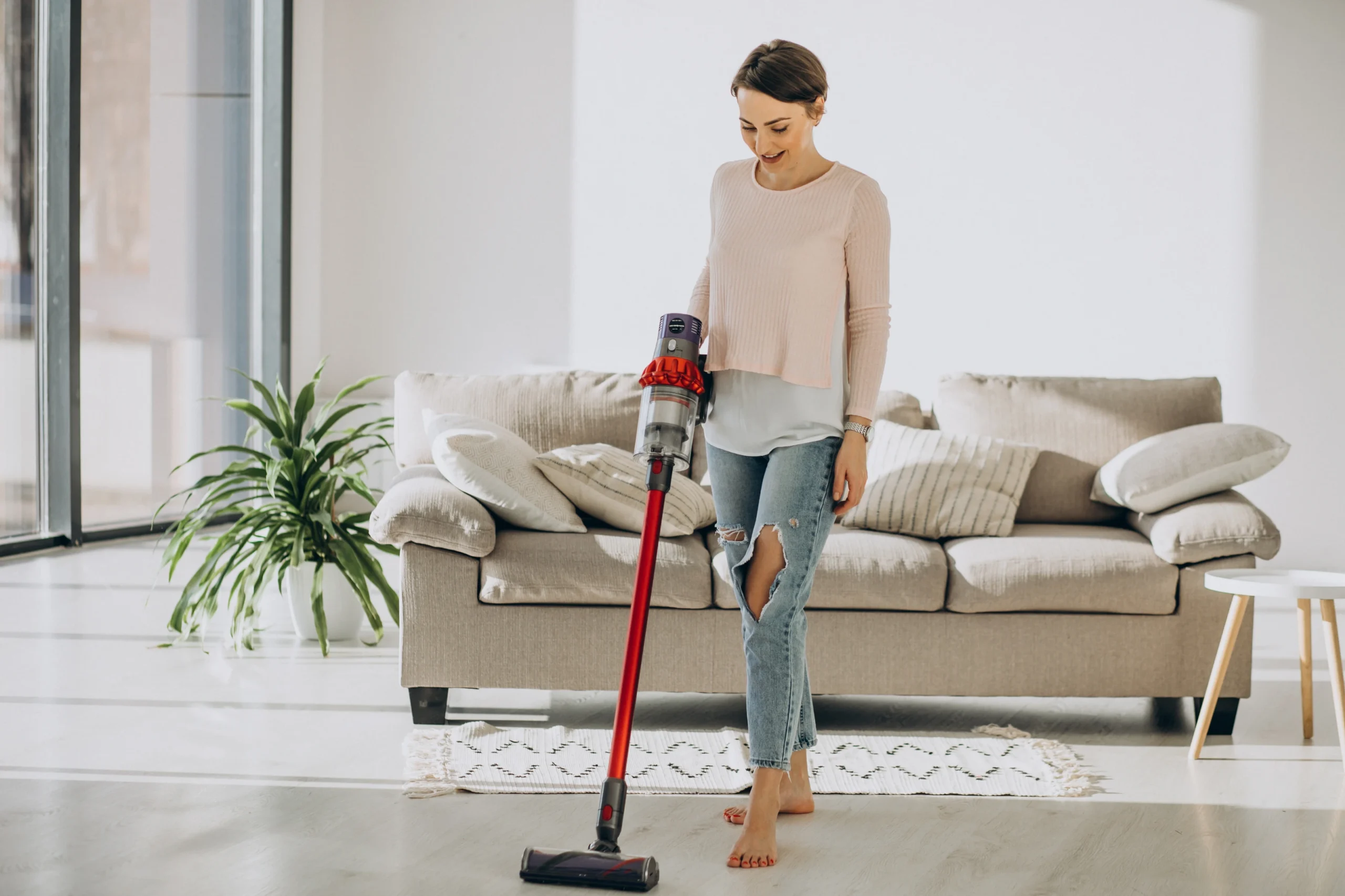 Professional cleaner vacuuming a bright modern living room during house cleaning service