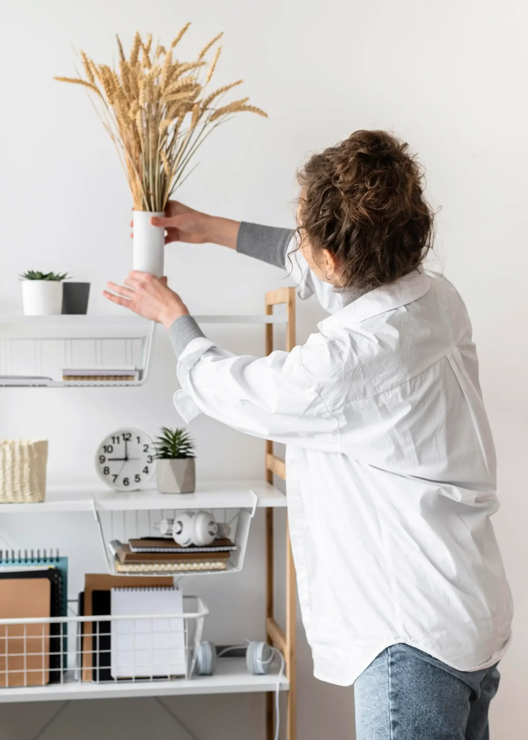 20-minute-Rule-in-Cleaning-Home-Organization A woman organizing a shelf and placing a vase while doing a quick tidy-up, showing the 20-minute Rule in Cleaning.