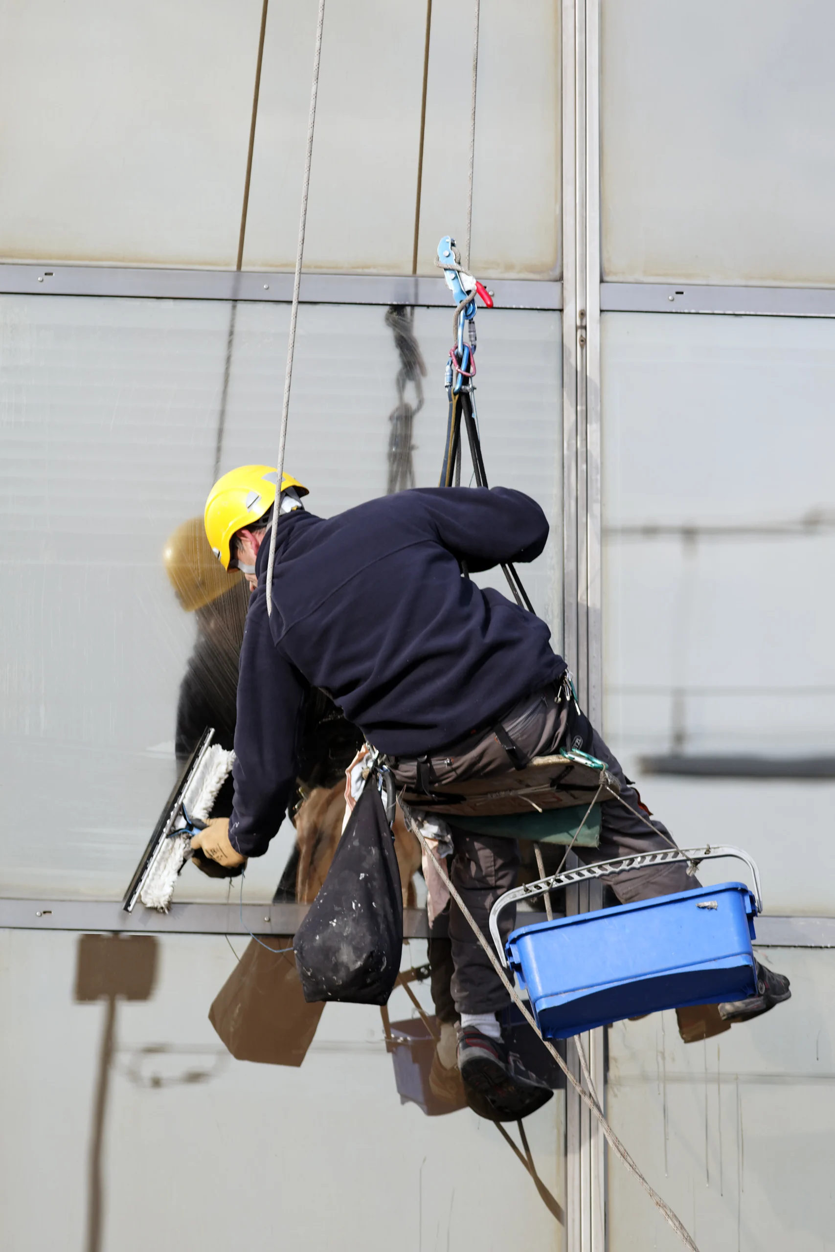 High rise window cleaners using harnesses and scaffolding for safe, streak-free glass cleaning